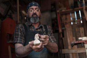 mestre de artesanato de colher em sua oficina com produtos artesanais de madeira e ferramentas trabalhando foto