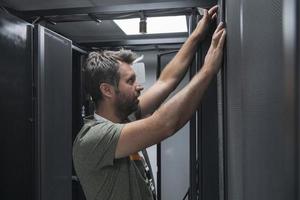 engenheiro de TI trabalhando na sala de servidores ou data center, o técnico coloca em um rack um novo servidor de supercomputador de mainframe de negócios corporativos ou fazenda de mineração de criptomoeda. foto