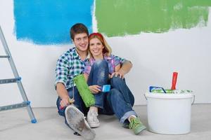 casal jovem feliz relaxando depois de pintar em casa nova foto