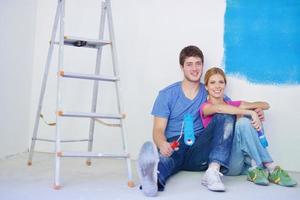 casal jovem feliz relaxando depois de pintar em casa nova foto