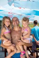 retrato de jovem pai feliz com filhas à beira-mar foto