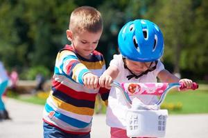 menino e menina no parque aprendendo a andar de bicicleta foto