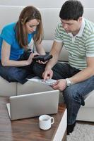 jovem casal trabalhando no laptop em casa foto