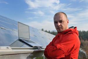 engenheiro usando laptop no campo de planta de painéis solares foto