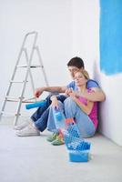 casal jovem feliz relaxando depois de pintar em casa nova foto