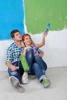 casal jovem feliz relaxando depois de pintar em casa nova foto