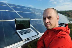 engenheiro usando laptop no campo de planta de painéis solares foto