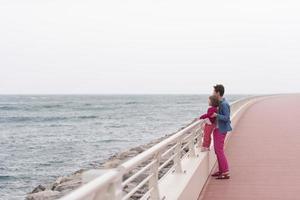 mãe e menina bonitinha no passeio à beira-mar foto