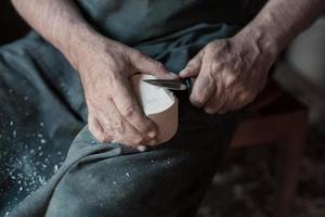 mãos esculpindo copo de madeira, trabalhando com cinzel close-up. oficina de madeira. processo de fabricação de utensílios de cozinha de madeira foto