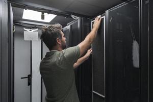 engenheiro de TI trabalhando na sala de servidores ou data center, o técnico coloca em um rack um novo servidor de supercomputador de mainframe de negócios corporativos ou fazenda de mineração de criptomoeda. foto