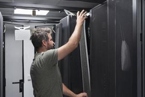 engenheiro de TI trabalhando na sala de servidores ou data center, o técnico coloca em um rack um novo servidor de supercomputador de mainframe de negócios corporativos ou fazenda de mineração de criptomoeda. foto