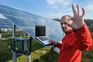 engenheiro usando laptop no campo de planta de painéis solares foto