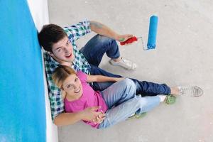 casal jovem feliz relaxando depois de pintar em casa nova foto