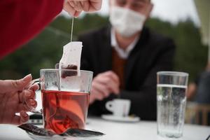 casal com máscara médica protetora tomando café em um restaurante foto