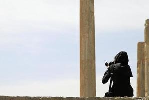 mulher no irã tirando uma foto em persépolis