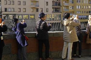 florença, itália, 2019 - turistas chineses fazem fila para tirar uma foto da famosa ponte vecchio com seus smartphones.