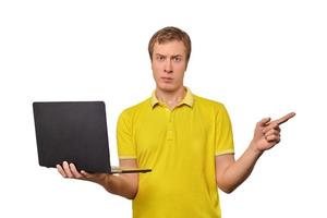 jovem intrigado com laptop apontando com o dedo isolado no fundo branco, rosto confuso masculino foto
