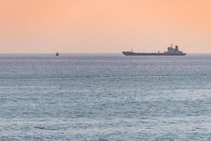 pequeno rebocador e grande cargueiro. belo pôr do sol sobre o mar. vista de viagem de tirar o fôlego, copie o espaço. foto