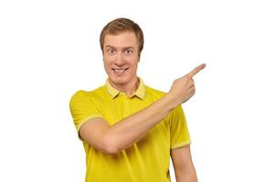 cara sorridente com cara engraçada em camiseta amarela, apontando o dedo para a direita, fundo branco foto