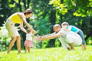 casal jovem feliz com seus filhos se divertir no parque foto