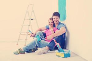 casal jovem feliz relaxando depois de pintar em casa nova foto