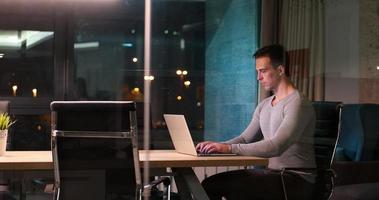 homem trabalhando no laptop no escritório escuro foto