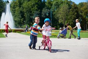 menino e menina no parque aprendendo a andar de bicicleta foto