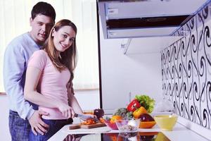 casal se diverte e prepara comida saudável na cozinha foto