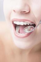 mulher saudável boca closeup com espelho de dentista foto