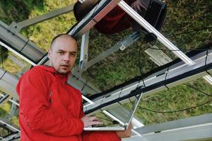 engenheiro usando laptop no campo de planta de painéis solares foto
