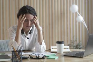 empresária espanhola cansada com os olhos fechados, sentado no local de trabalho no escritório, sofrendo de dor de cabeça foto