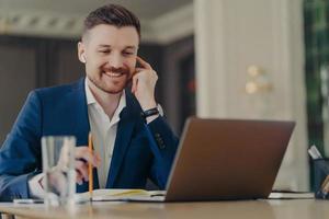 CEO feliz bem sucedido tendo reunião online, usando laptop e fones de ouvido foto