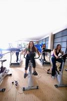 mulheres malhando em bicicletas giratórias na academia foto