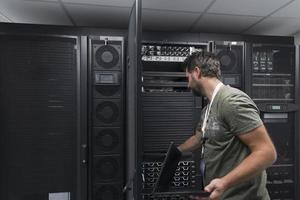 engenheiro de data center usando teclado em uma instalação especializada em sala de servidores de supercomputador com administrador de sistema masculino foto