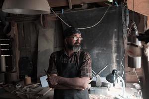 mestre de artesanato de colher em sua oficina com ferramentas e produtos artesanais de madeira foto