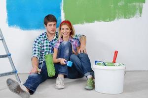 casal jovem feliz relaxando depois de pintar em casa nova foto