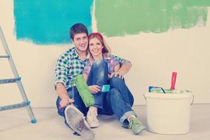 casal jovem feliz relaxando depois de pintar em casa nova foto