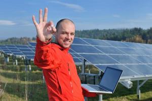 engenheiro usando laptop no campo de planta de painéis solares foto