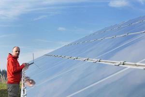 engenheiro usando laptop no campo de planta de painéis solares foto