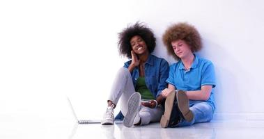 casal multiétnico sentado no chão usando um laptop e tablet foto