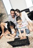 feliz jovem família se divertir e trabalhar no laptop em casa