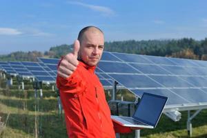 engenheiro usando laptop no campo de planta de painéis solares foto