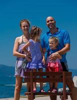 retrato de jovem família feliz com filhas à beira-mar foto