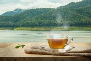 xícara de chá com serapilheira na mesa de madeira e o fundo do pântano foto