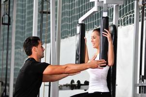 mulher no ginásio de fitness malhando com personal trainer foto