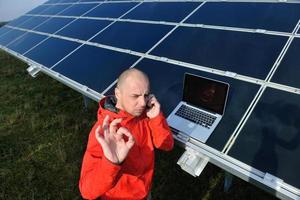 engenheiro usando laptop no campo de planta de painéis solares foto