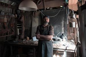 mestre de artesanato de colher em sua oficina com ferramentas e produtos artesanais de madeira foto