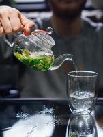 chá verde quente com hortelã, vapor sobe, fundo escuro foto