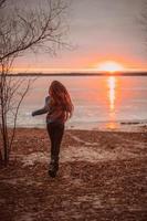 mulher aproveitando o tempo relaxante à beira do belo lago ao nascer do sol. foto