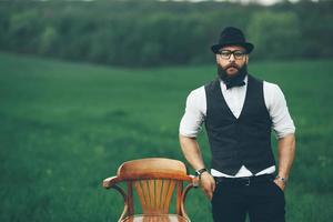 homem com barba, pensando no campo perto da cadeira foto